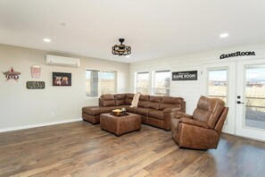 A spacious living room with a sectional sofa, a recliner, and a popcorn bucket on a coffee table. There are wall decorations including a 'Welcome' sign, a popcorn bucket, and a cinema sign. A 'Game Room' sign is visible on the wall. - Casa Blanca Old Town w/ Pool & Red Rock Views (Cottonwood)