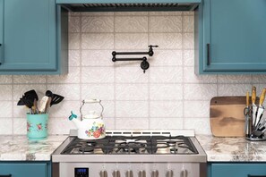 A kitchen with teal cabinets, a gas stove, a decorative teapot, and a wooden cutting board. - Casa Blanca Old Town w/ Pool & Red Rock Views (Cottonwood)