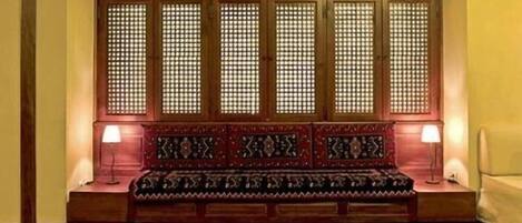 Una habitación tradicional con un banco de madera, dos lámparas de pared y una alfombra estampada.