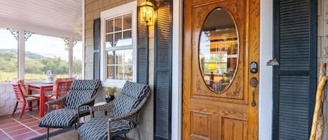 A porch with wicker furniture, a wooden door with a glass panel, and a lantern.