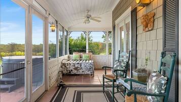 A covered porch with a table and chairs, a ceiling fan, and a view of the outdoors.