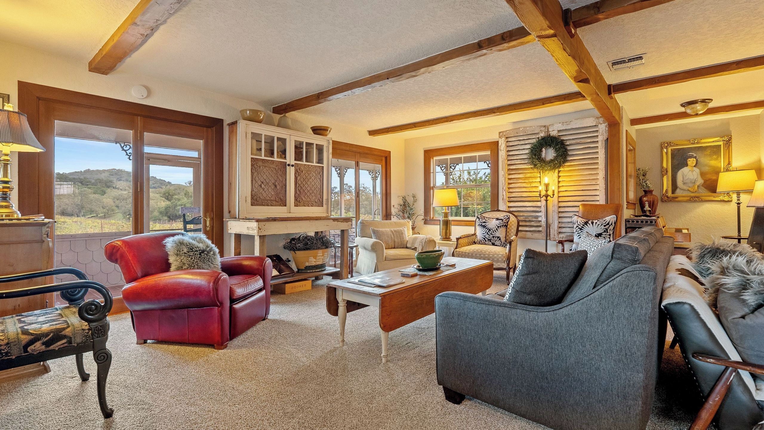 A cozy living room with a fireplace, comfortable seating, and a view of the outdoors.