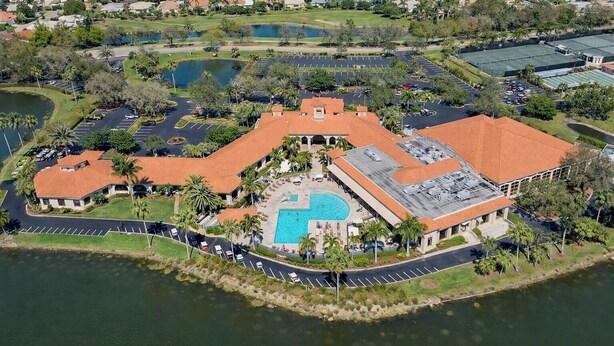Vista aerea di un resort con piscina, aree parcheggio e campo da golf.