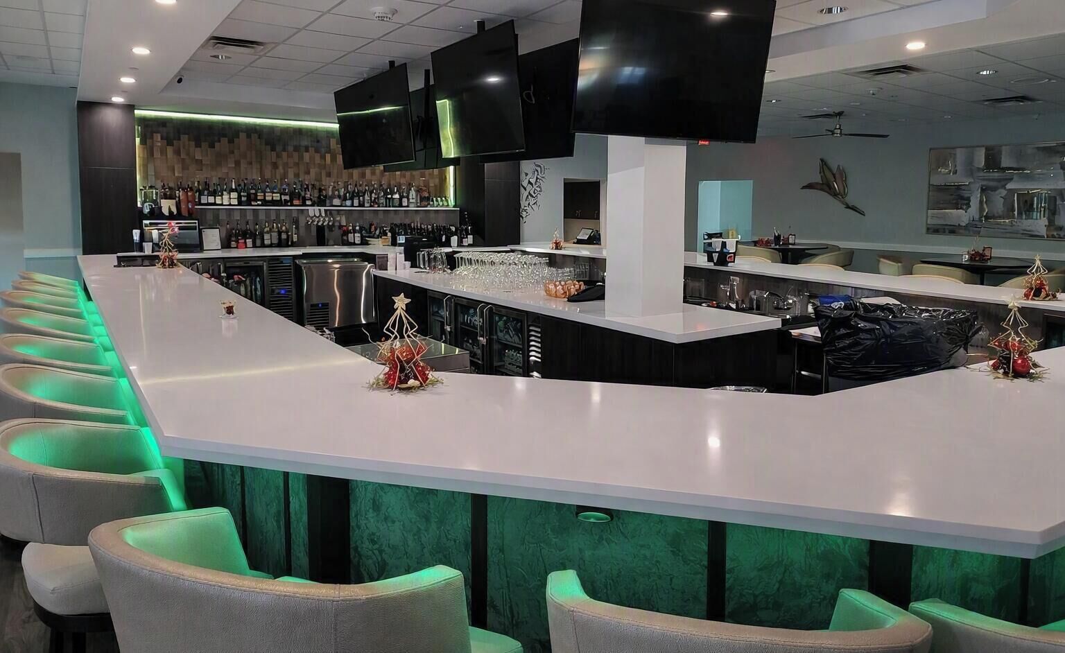 A bar area with a long counter, multiple seating options, and a variety of bottles and glasses.