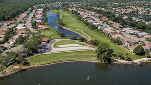 Un quartiere residenziale con un campo da golf, un lago e case.