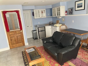A living room with a black leather sofa, a glass-top coffee table, and a patterned rug. - Garden level studio apartment downtown Boulder (Boulder)