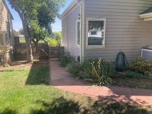 A residential property with a paved driveway, a wooden fence, and a variety of plants. - Garden level studio apartment downtown Boulder (Boulder)