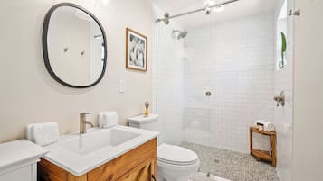 A bathroom with a double sink vanity, a toilet, a shower with a glass door, and a mirror.