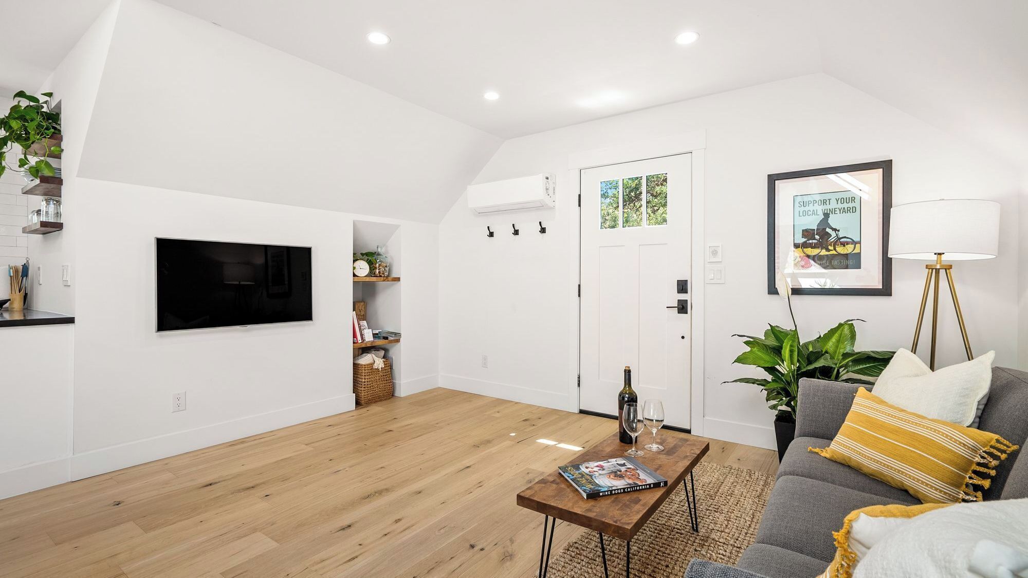A modern living room with a flat-screen TV, a coffee table with a magazine, a sofa with cushions, and a floor lamp.