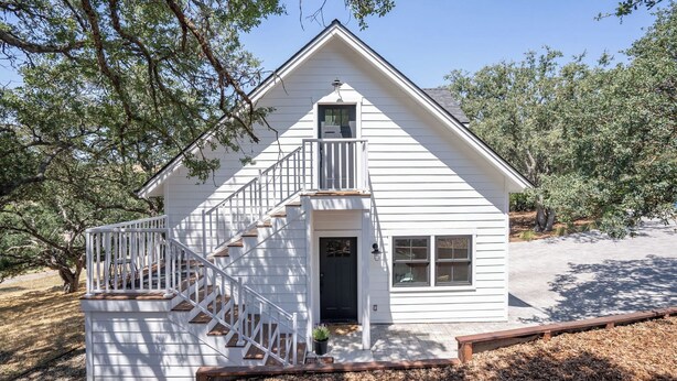 A white two-story house with a front porch, a staircase, and a small balcony. - The Nook on Hilltop by Avantstay Skylit Loft + Private Entry + Induction Kitchen Walk to Downtown Paso Robles Wine Country (Paso Robles)