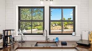 A kitchen with a large window, a coffee maker, a sink, and a countertop. - The Nook on Hilltop by Avantstay Skylit Loft + Private Entry + Induction Kitchen Walk to Downtown Paso Robles Wine Country (Paso Robles)