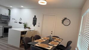 Een moderne keuken met een eethoek, een klok en een welkomstbord.