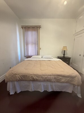 A bedroom with a bed, a nightstand, a lamp, and a window with curtains. - Historic Victorian/Walk to Midtown restaurants (Sacramento)
