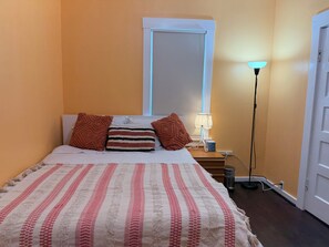 A bedroom with a bed, pillows, a bedside lamp, and a nightstand.