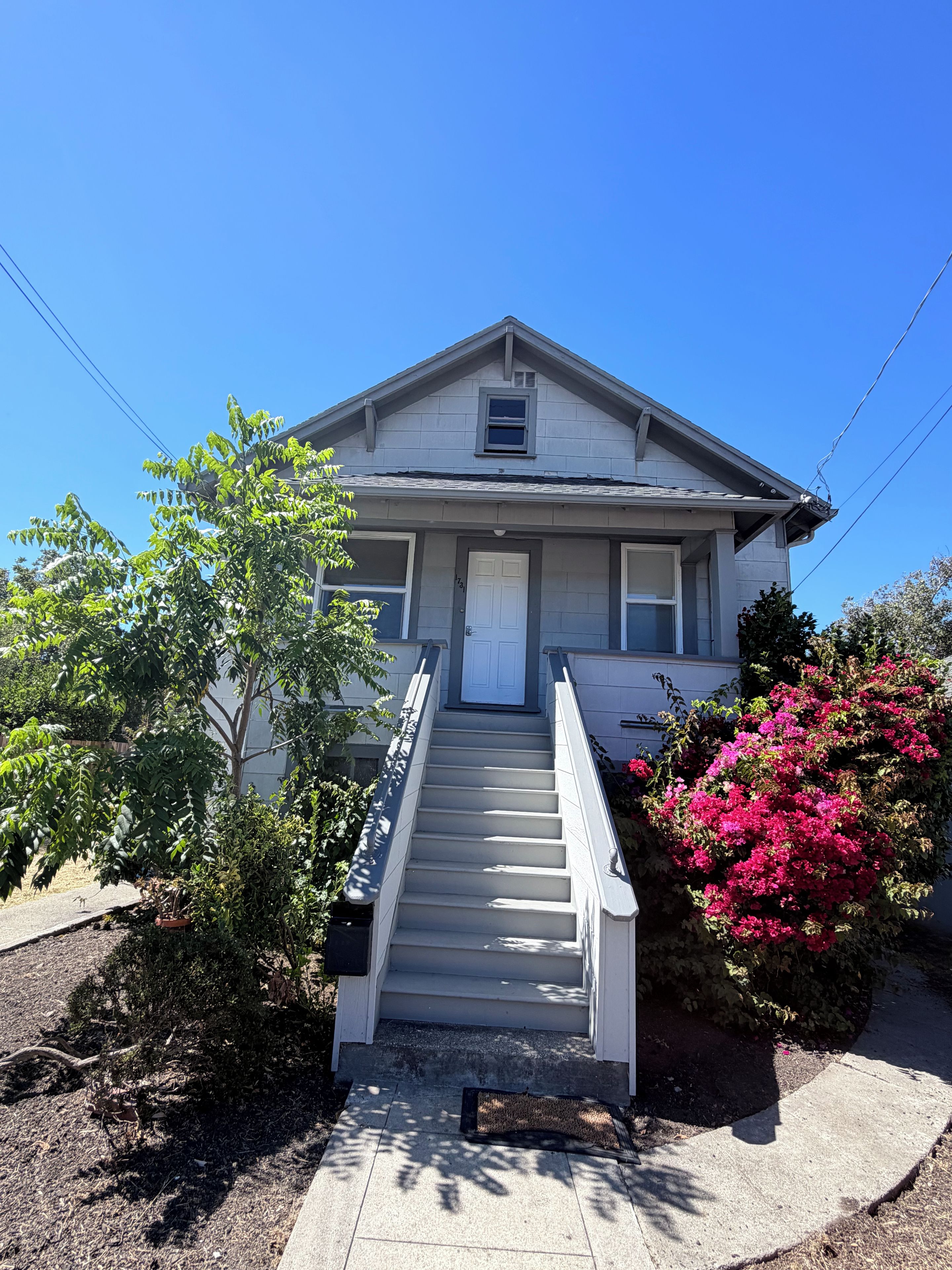 A two-story house with a front porch, a staircase, and a small window above the door.