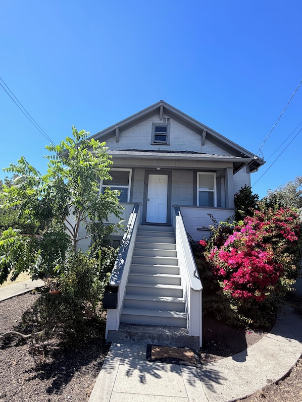 A two-story house with a front porch, a staircase, and a small window above the door.