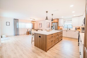 A modern kitchen with a central island, wooden cabinets, and stainless steel appliances. - Modern Designer 3BD 2BA Pool Retreat 5 min to Beach (Seminole)