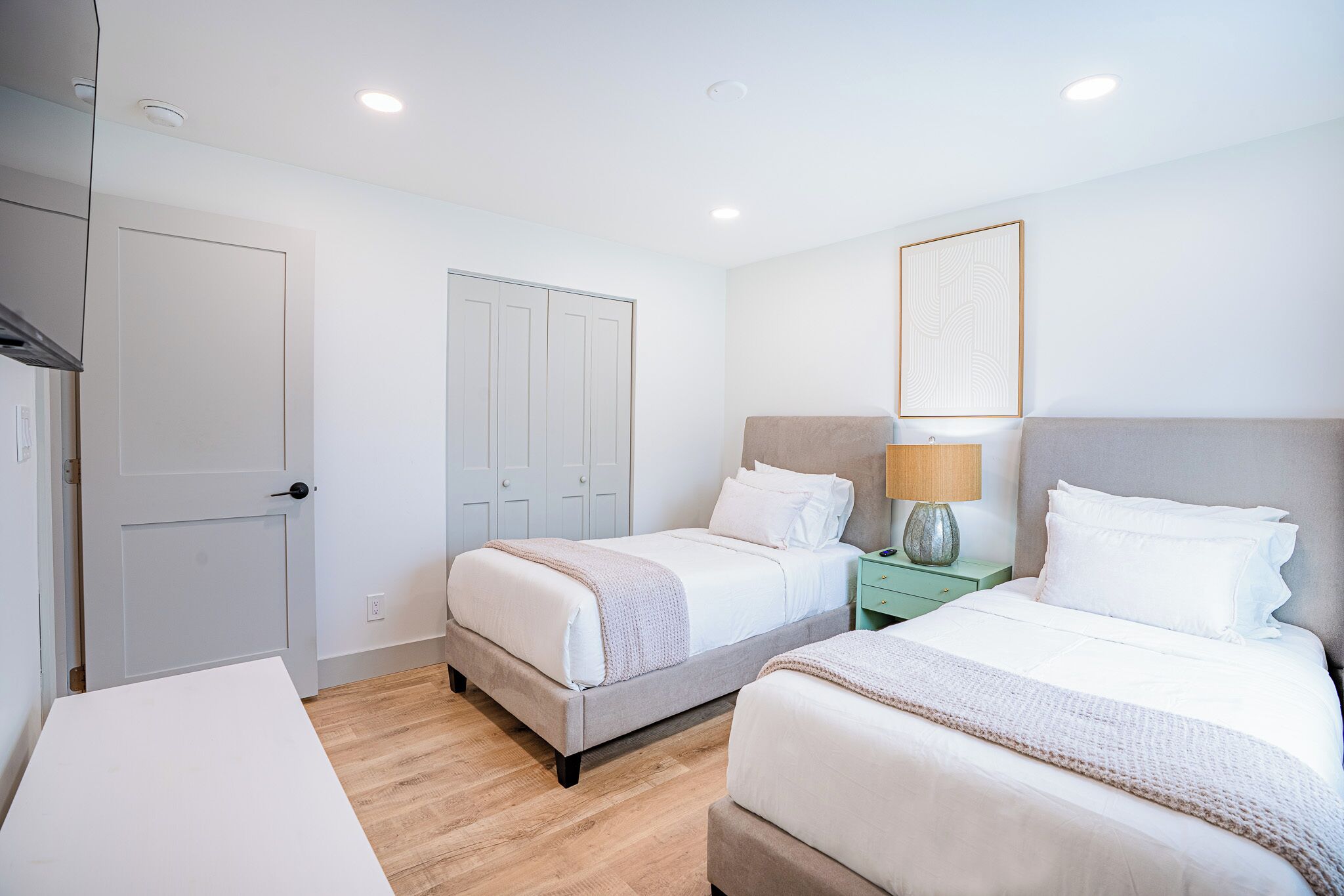 A hotel room with two beds, a desk, and a wardrobe.