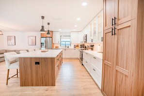 A modern kitchen with a central island, wooden cabinets, and stainless steel appliances. - Modern Designer 3BD 2BA Pool Retreat 5 min to Beach (Seminole)