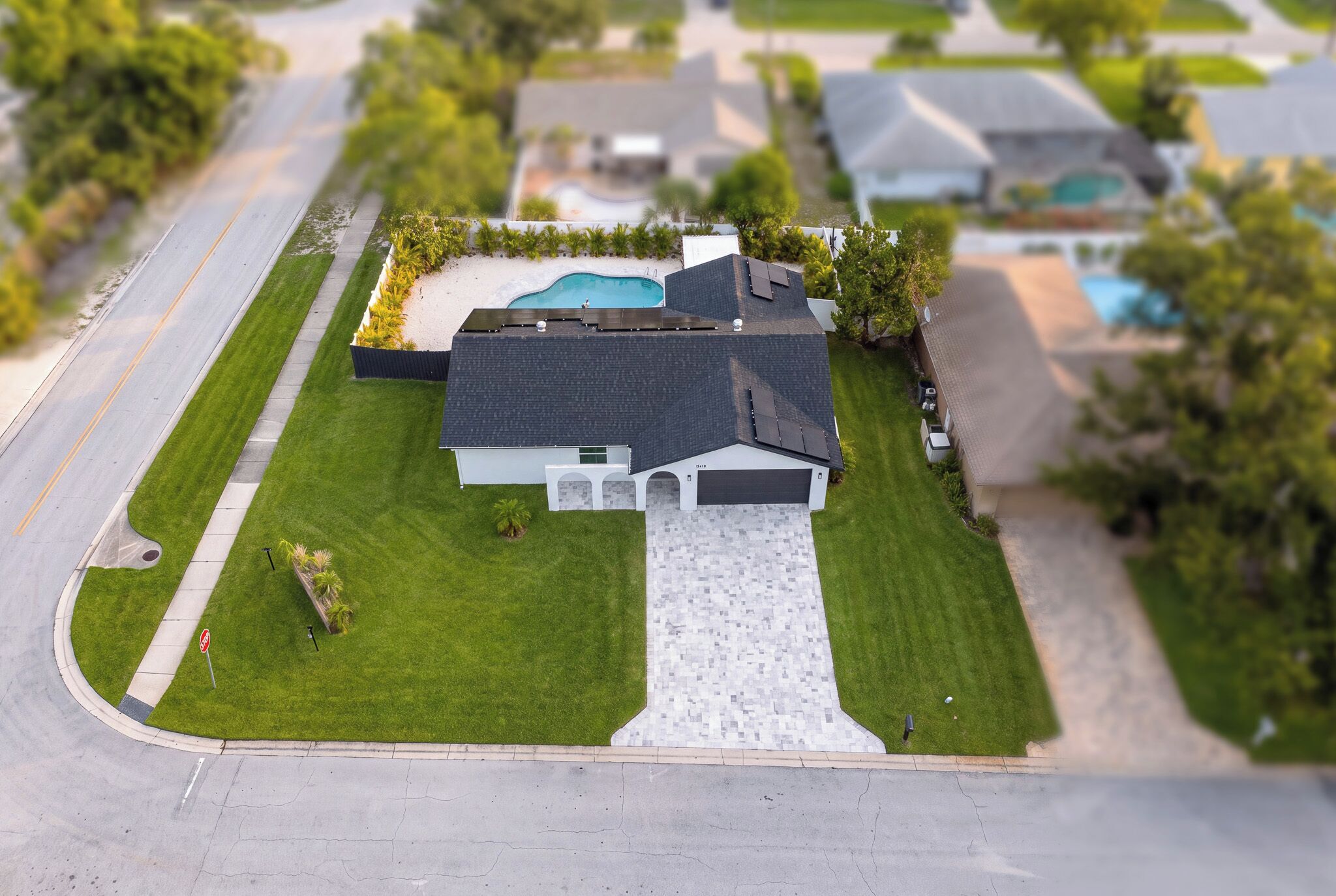 A residential property with a swimming pool, a garage, and a well-maintained lawn.