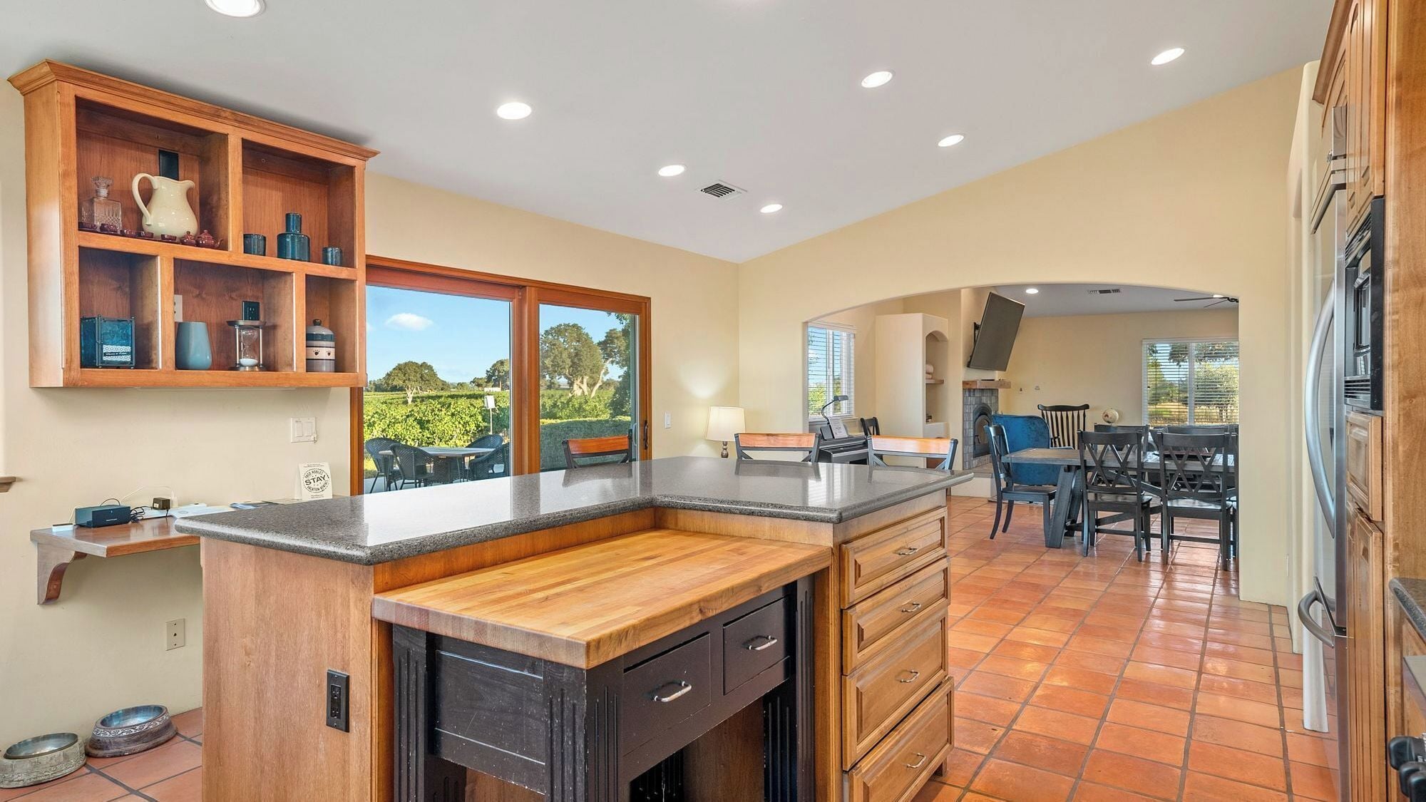 Cocina con encimera de madera, estante empotrado y vistas al exterior.