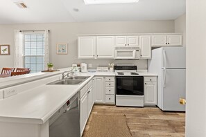 A modern kitchen with white cabinetry, a dishwasher, a stove, and a refrigerator. - River Oaks 49I Myrtle Beach | Great Fall Price! (Myrtle Beach)