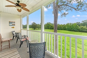 A covered porch with a ceiling fan, a view of a grassy field, and a sign with cabin rules. - River Oaks 49I Myrtle Beach (Myrtle Beach)