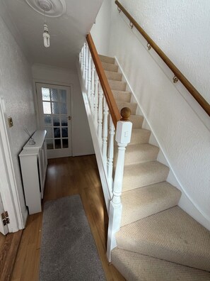 A staircase with white balusters and a wooden handrail, carpeted steps, and a radiator on the floor. - 5 Bed Contractor / Families and Groups accommodation (Ipswich)