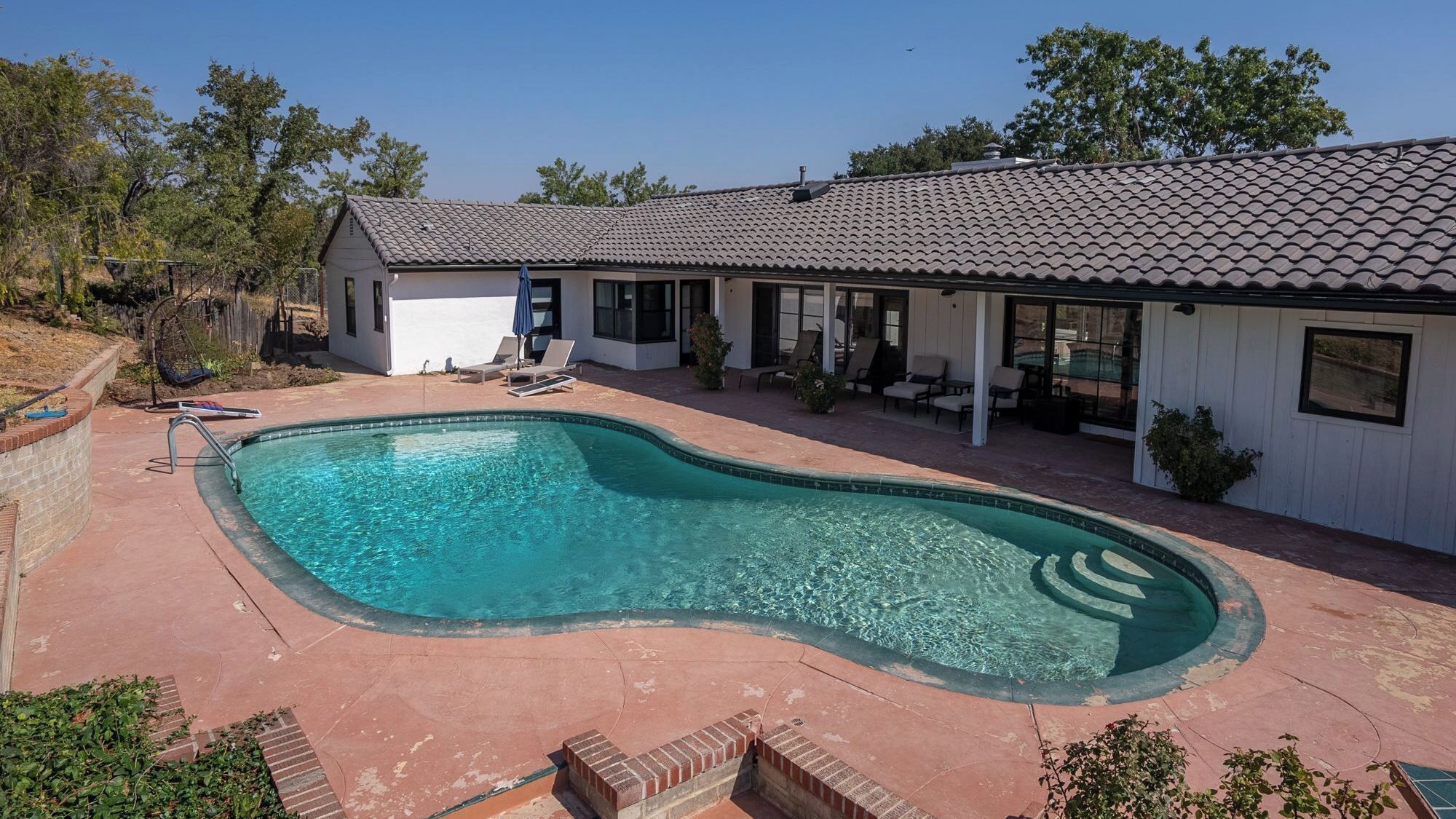 A residential property with a swimming pool, a covered patio, and a detached garage.