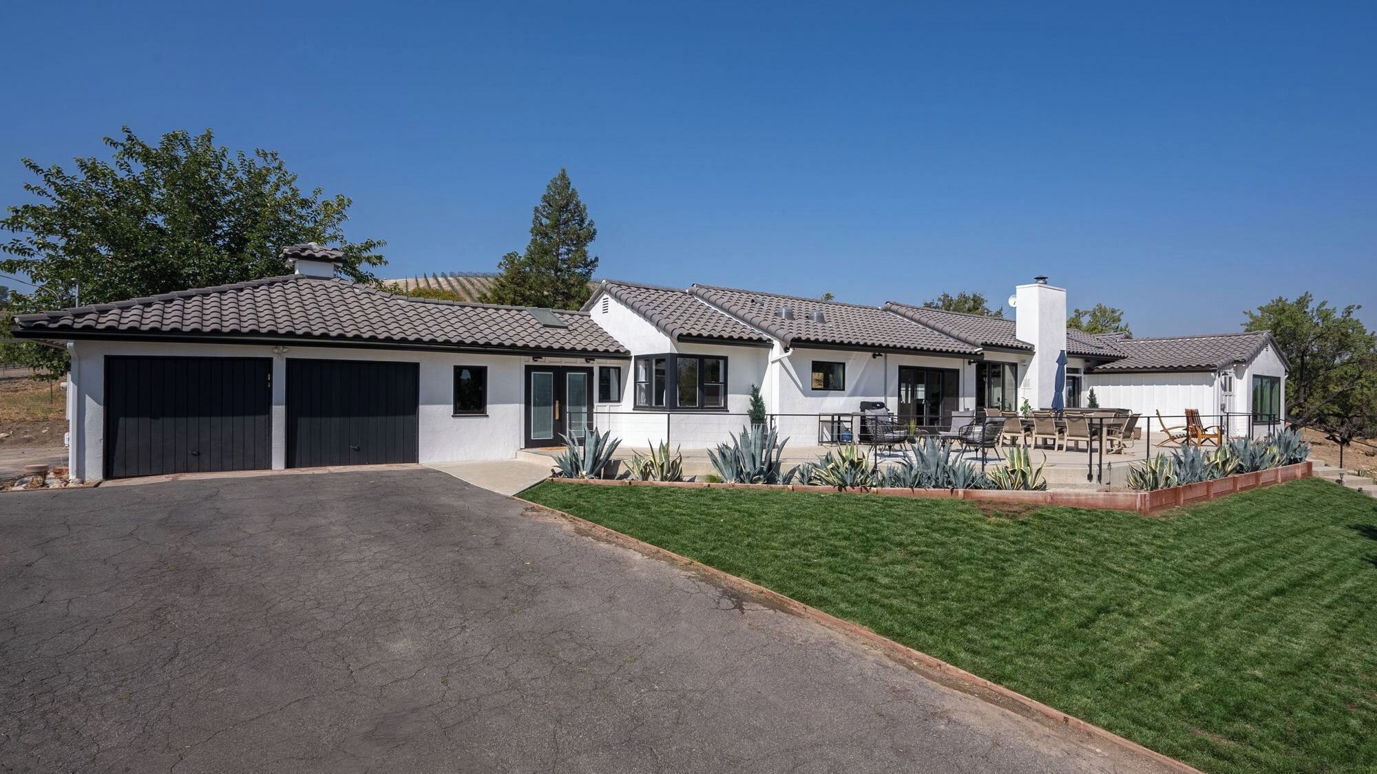 A two-story house with a garage, a patio with seating, and a well-maintained lawn.