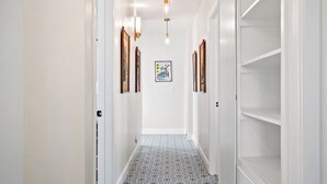 A hallway with patterned flooring, white walls, and framed pictures on the walls. - Kiler Views by Avantstay Pool + Spa + Vineyard Views Downtown Paso Robles (Paso Robles)