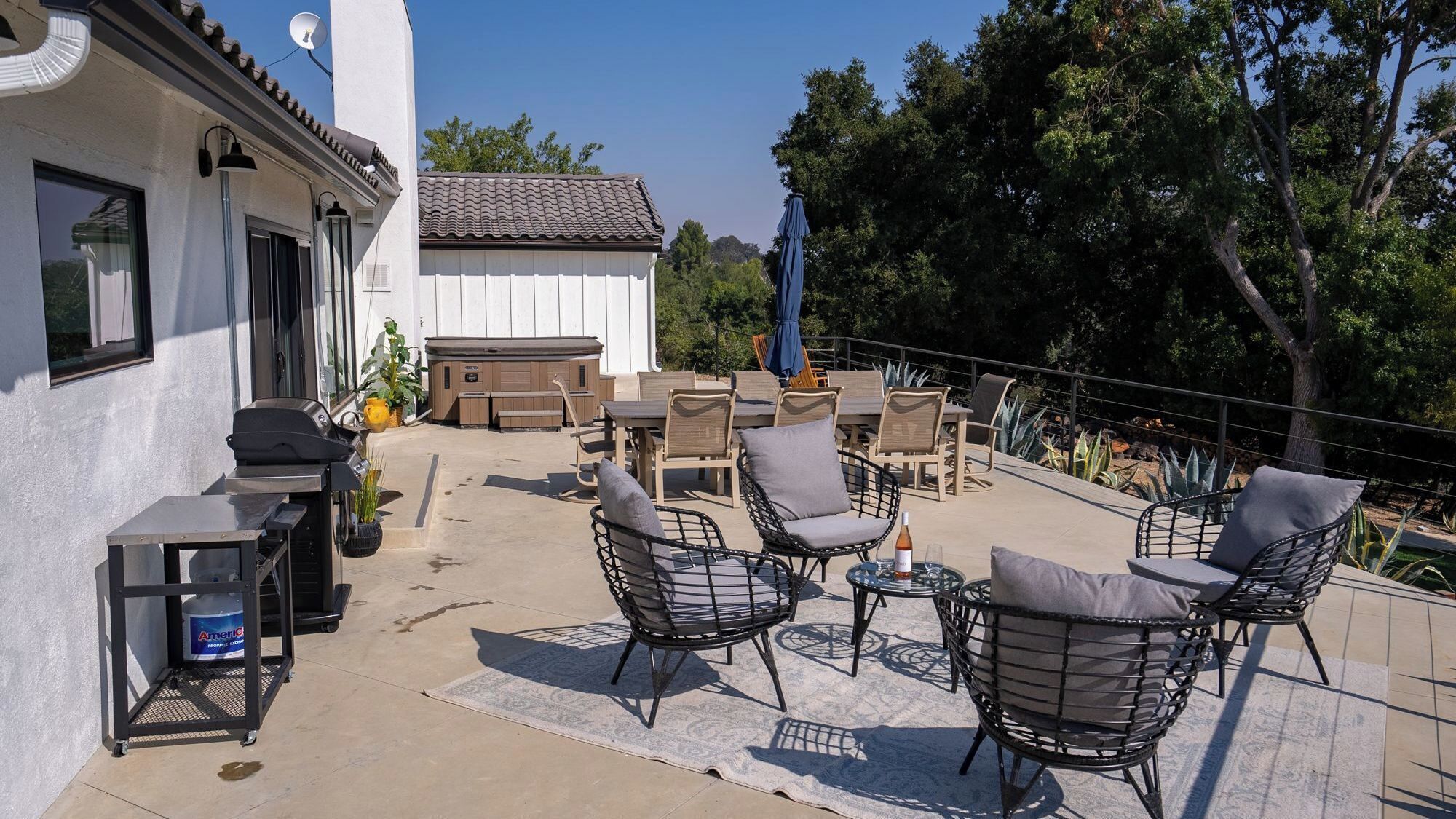 Un patio exterior con sillas de mimbre, una parrilla y una mesa de billar.