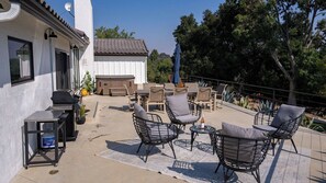 Eine Terrasse im Freien mit Korbstühlen, einem Grill und einem Billardtisch.