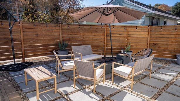 An outdoor patio with a wooden fence, a table with chairs, and a patio umbrella. - Prickly Pear Paso by Avantstay Fire Pit + BBQ Patio Walkable Downtown Paso (Paso Robles)