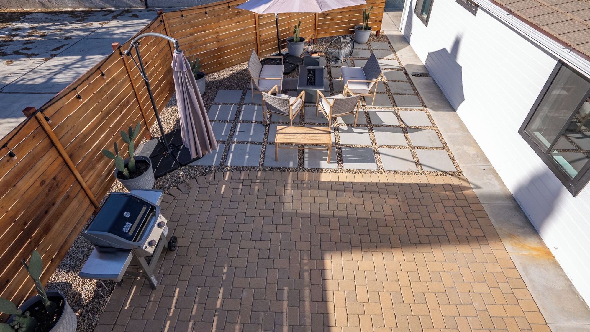A patio with a grill, seating, and a wooden fence.