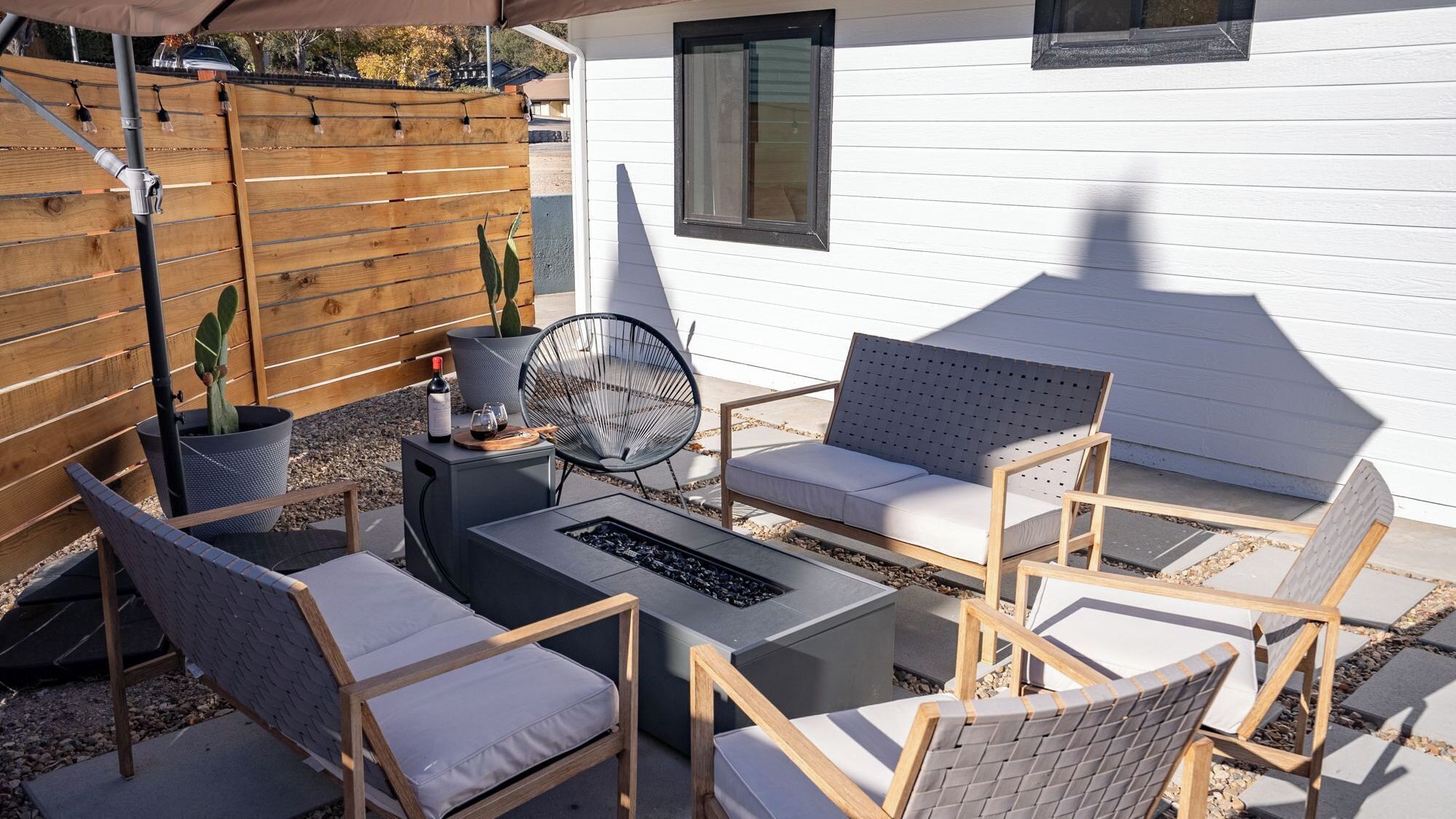 An outdoor patio with a sofa, chairs, a table, and a fire pit.