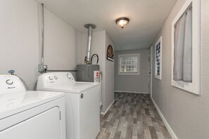 A laundry room with two front-loading washers and dryers, a water heater, and a stop sign on the wall. - Charming 2-bedroom house with AC in charming Springfield (Springfield)