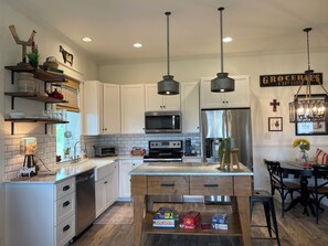 A modern kitchen with white cabinetry, a central island, and a dining area with a chandelier.