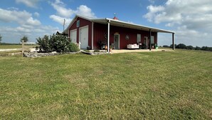 Een rode schuur met een overdekte veranda, omringd door een grasveld.