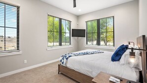 A bedroom with a bed, a TV mounted on the wall, and a window with blinds. - Steel City Cellars by Avantstay 2 Ensuite Beds + Vineyard Views Paso Robles Wine Country (San Miguel)
