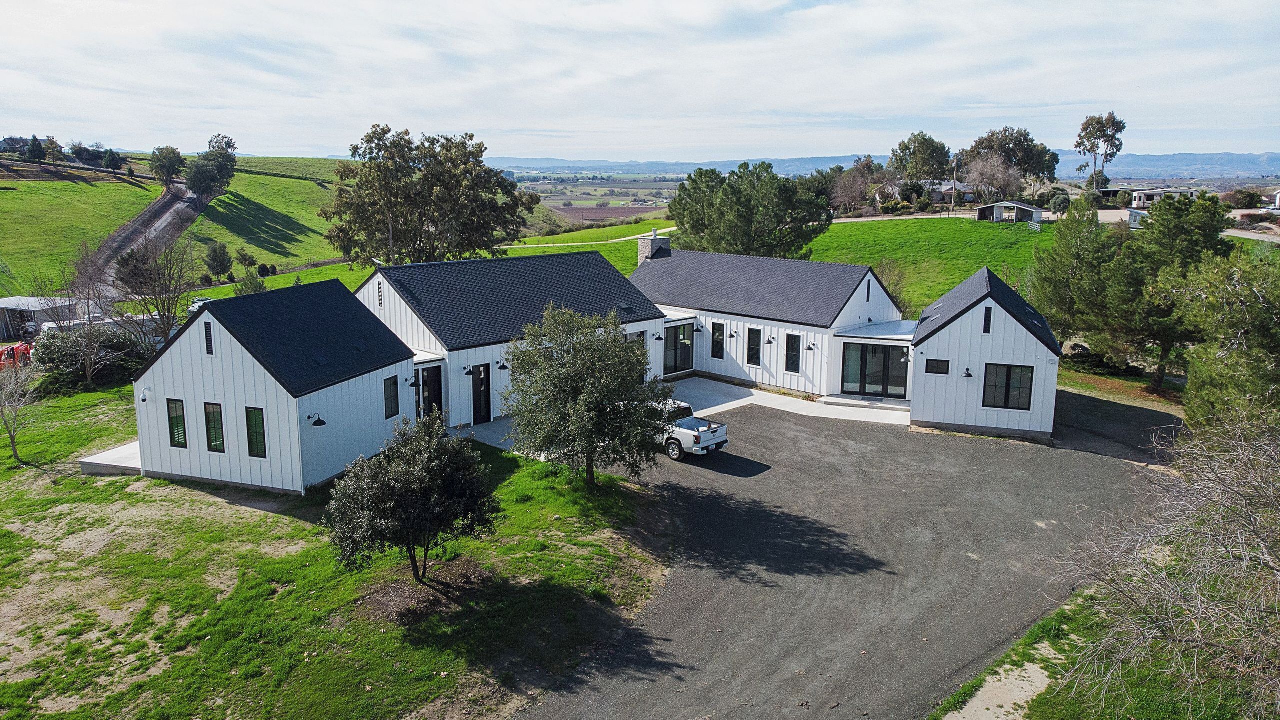 A white two-story house with a driveway and a parked vehicle.