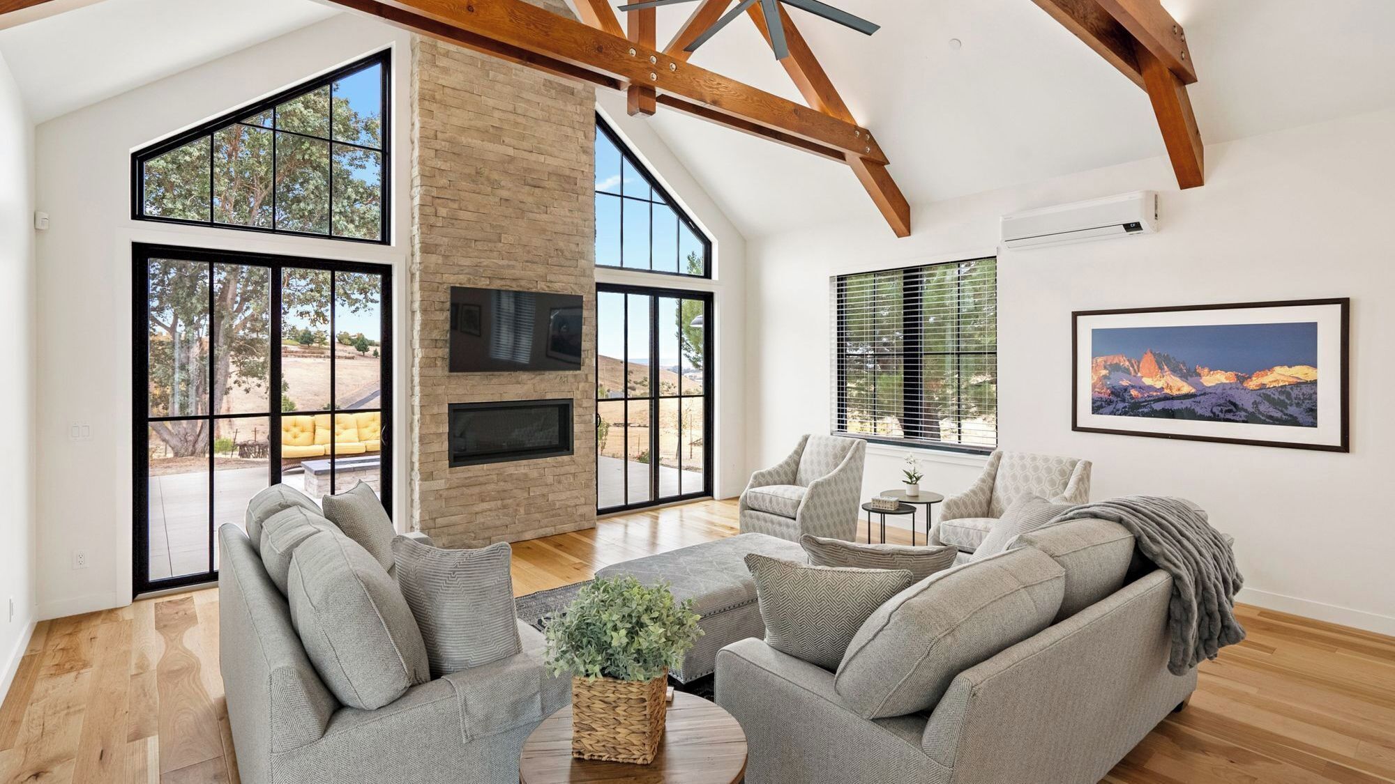 Un salón amplio con chimenea, ventanas grandes y un techo alto con vigas a la vista.