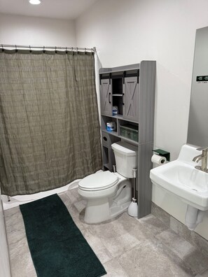 A bathroom with a toilet, sink, and storage cabinets.