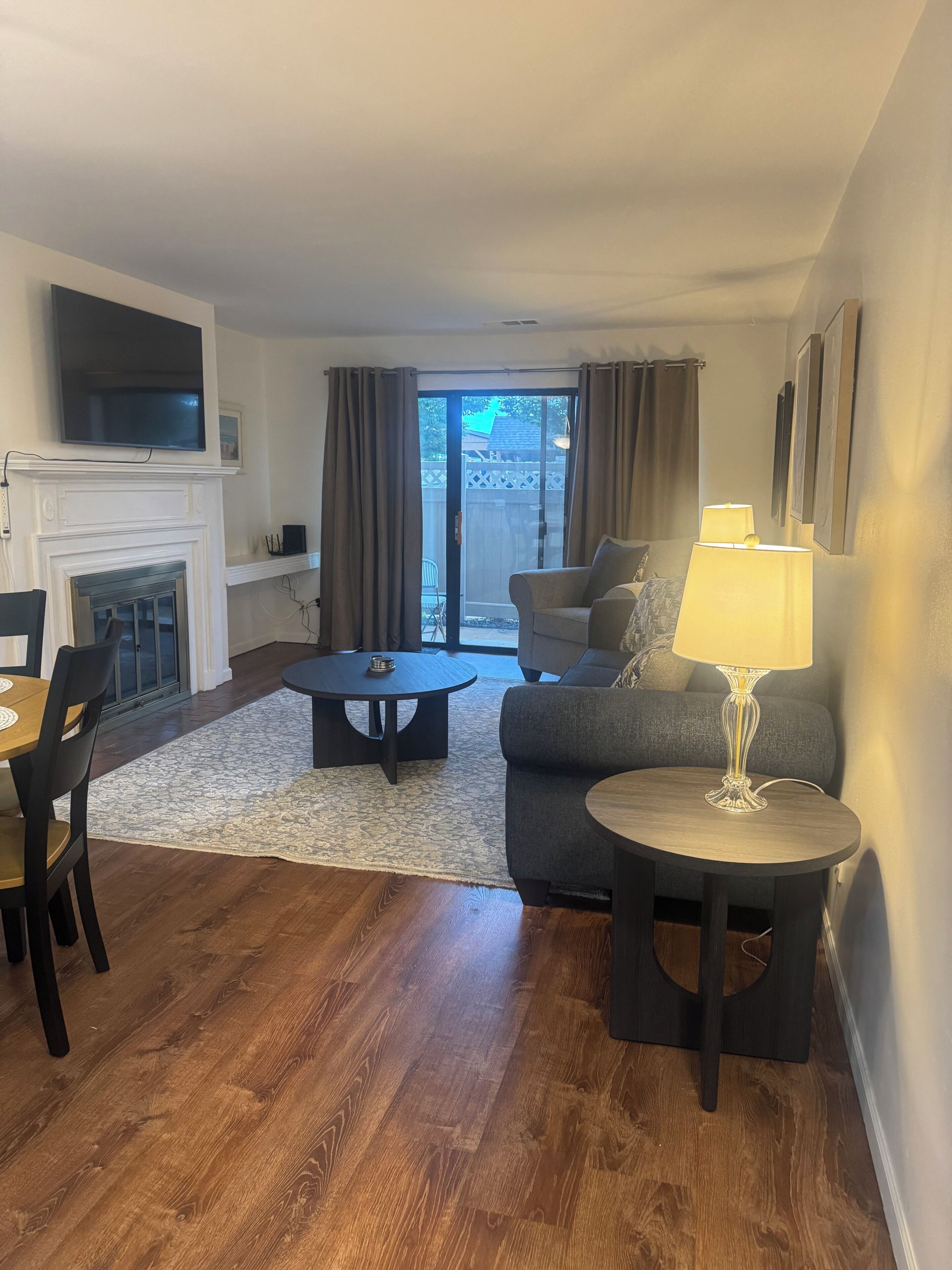 A living room with a fireplace, a television mounted above it, a sofa, a coffee table, and a lamp.