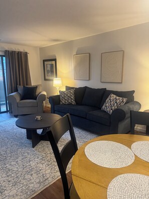 Ein Wohnzimmer mit Sofa, Sesseln, Couchtisch und Lampe.