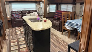 A compact RV interior with a kitchenette, a seating area, and a dining space.