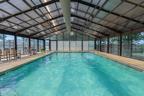 A covered swimming pool with a metal roof, wooden chairs, and a view of the outside. - Caddy Shack | Pointe Royale 3BR Condo w/ Pools + Golf Views (PR 61-8) (Branson)
