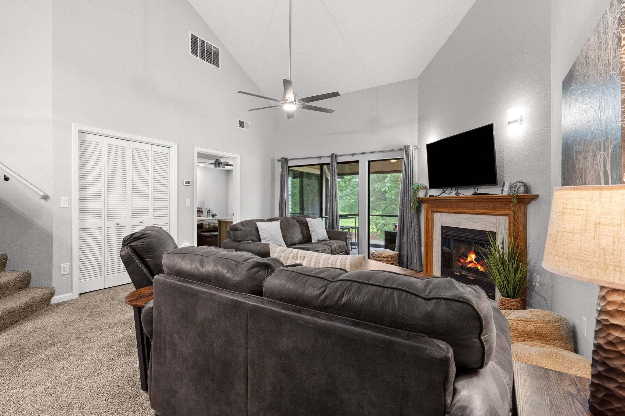 A living room with a fireplace, a television, and a ceiling fan.