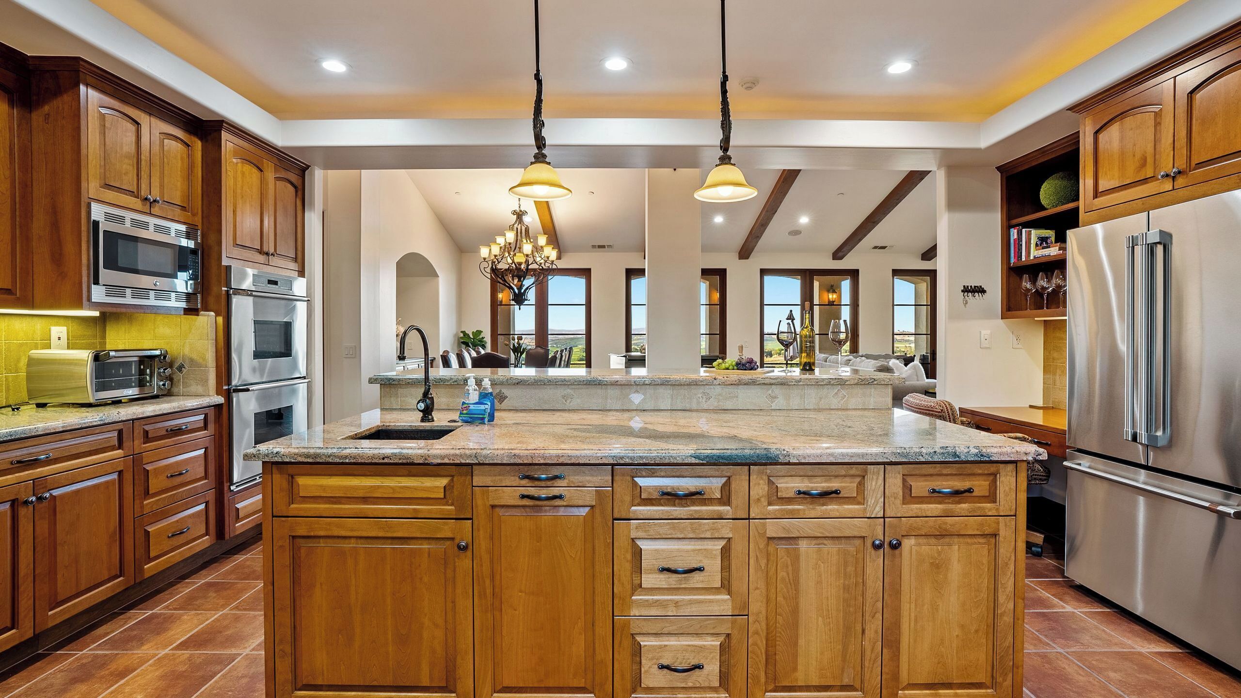 A spacious kitchen with wooden cabinets, stainless steel appliances, and a large island with a sink.