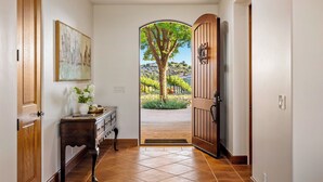 A hallway with a wooden door leading to a garden view. - Krisyn Vineyards by Avantstay Private Pool + Spa Templeton Wine Country (Templeton)